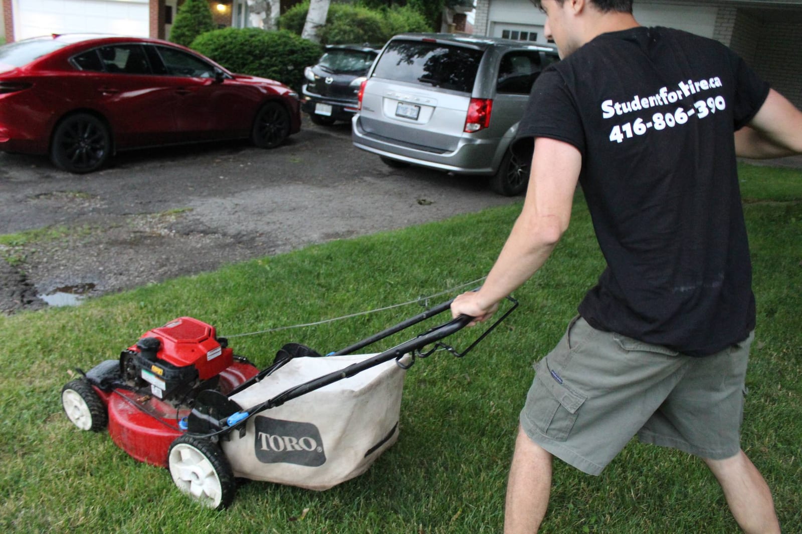 Student mowing a lawn in a Student For Hire shirt